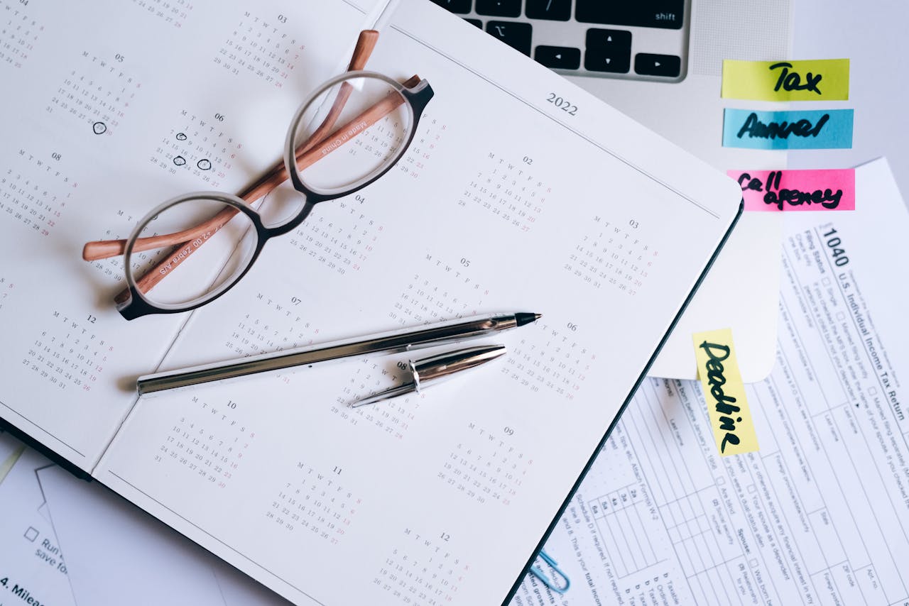 Overhead view of a desk with glasses, a pen, calendar, and tax documents.